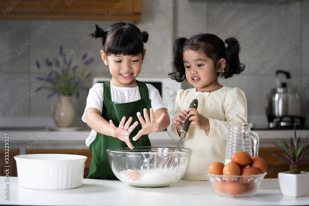 亚洲孩子喜欢在厨房做饭。快乐的亚洲孩子正在准备面团，烤饼干