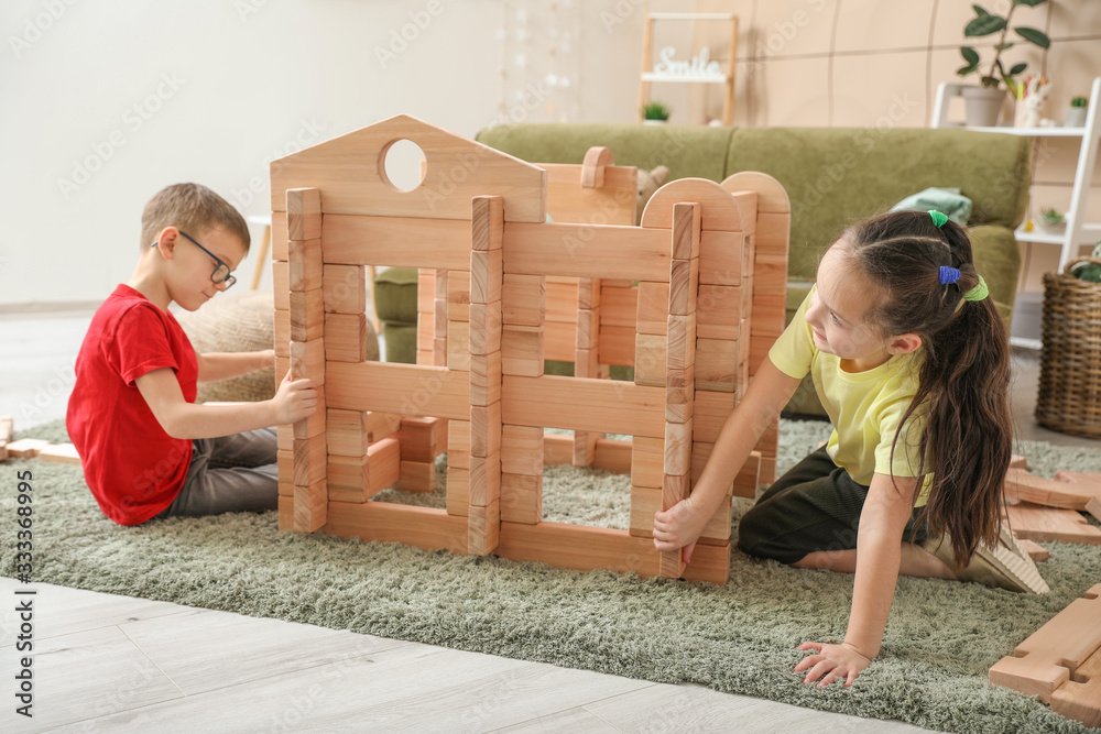 Little children playing with take-apart house at home