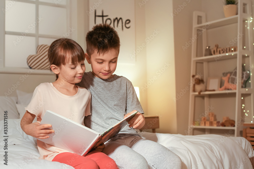 Little children reading bedtime story at home