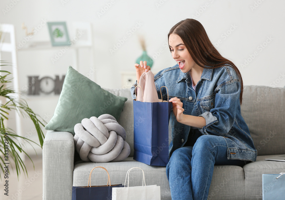 Happy young woman with shopping bags at home