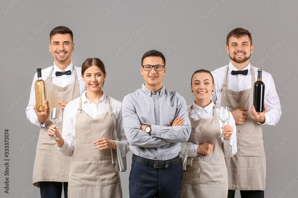 Group of waiters with teacher on grey background