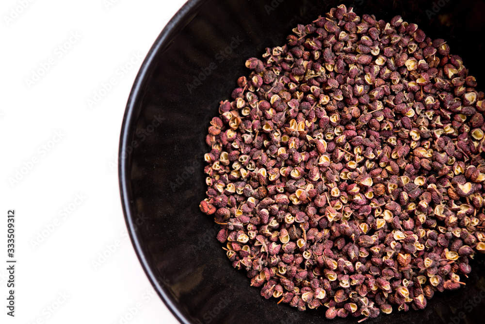 Scented Sichuan pepper in  the black bowl on the white table isolated image. Sichuan pepper or Chine