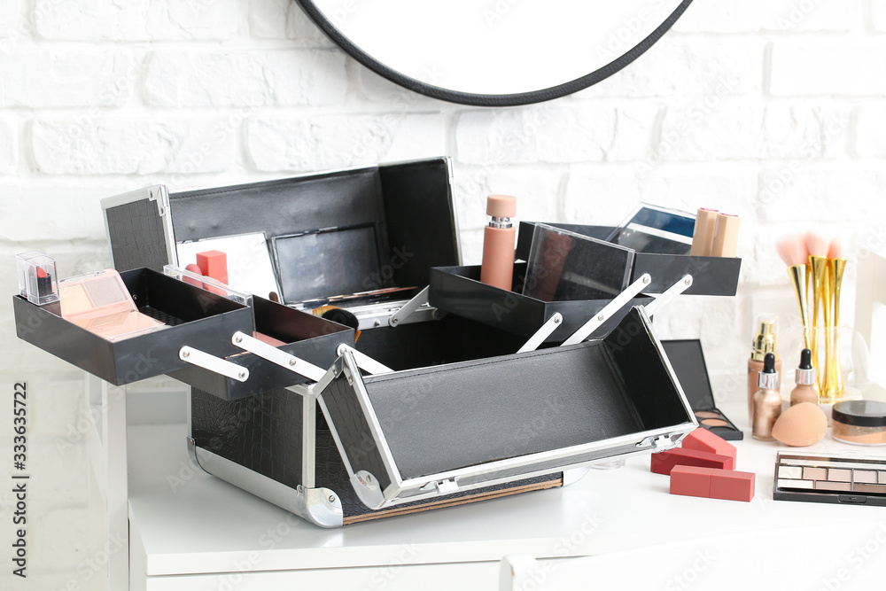 Case of professional makeup artist with decorative cosmetics on table