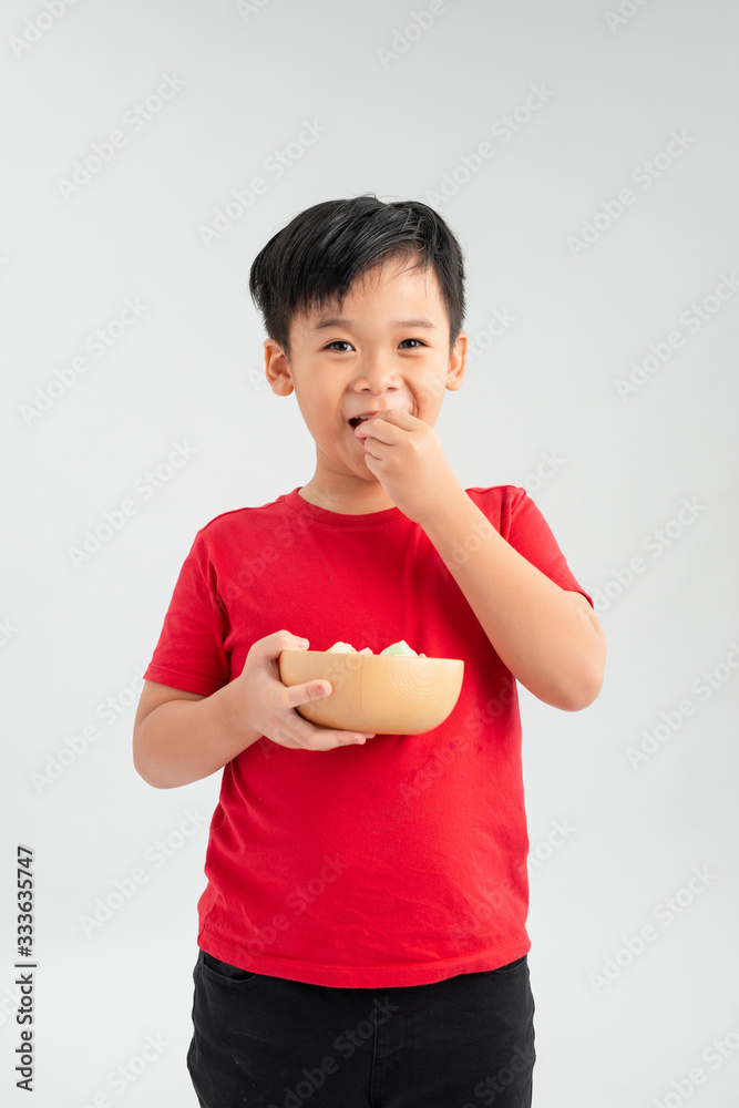 Cute little boy smiling and holding a bowl of candy.