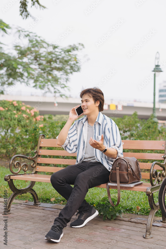 一名年轻男子在公园骑自行车坐在长椅上打电话