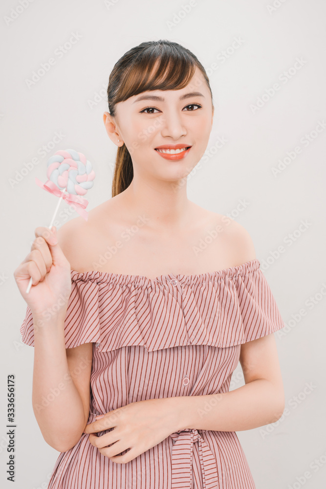 Asian teenager holding and eating colorful lollipop