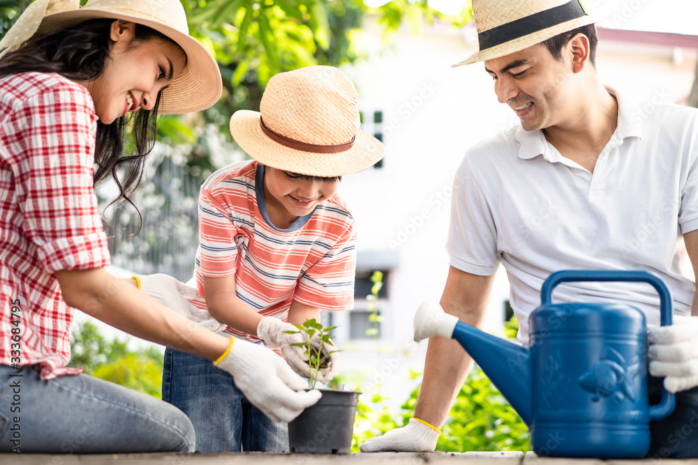 亚洲可爱的年轻家庭一起在家门口种一棵树。男孩拿着一些土，母亲拿着