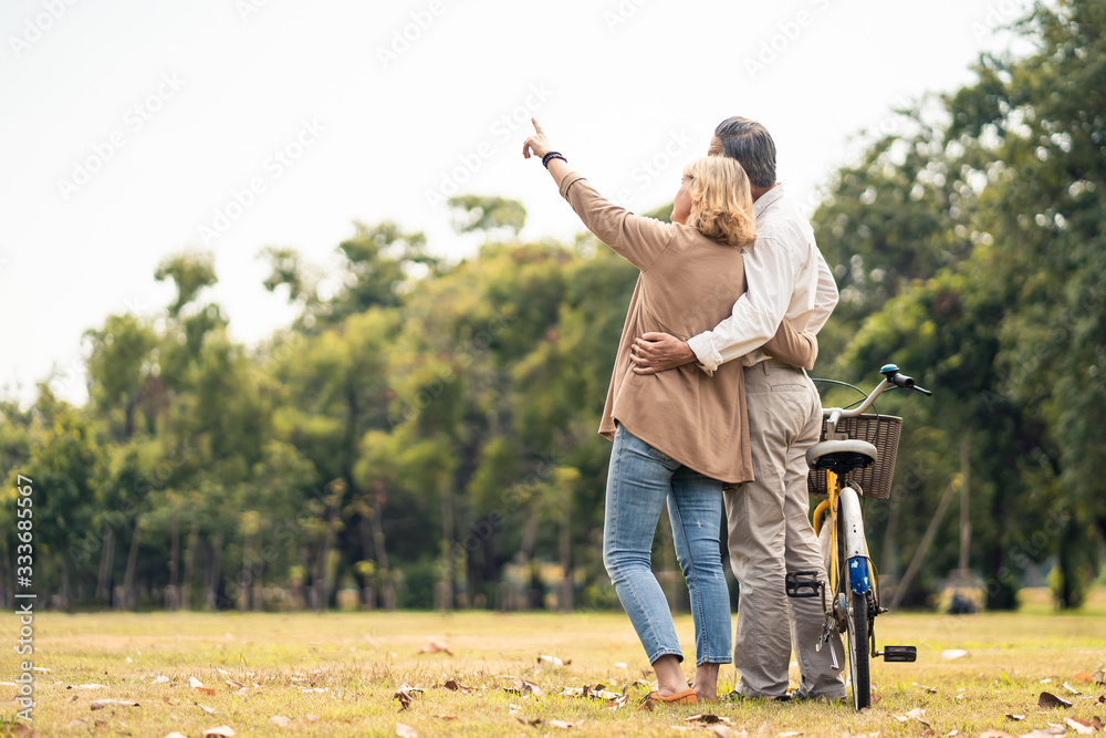 高加索老年夫妇在公园里抱着自行车站着。成熟快乐，享受慢生活