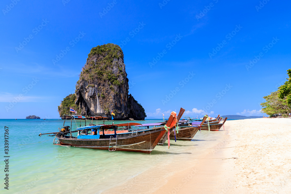 Long tail boat and turquoise crystal clear sea water with limestone cliff and mountain at Phra Nang 