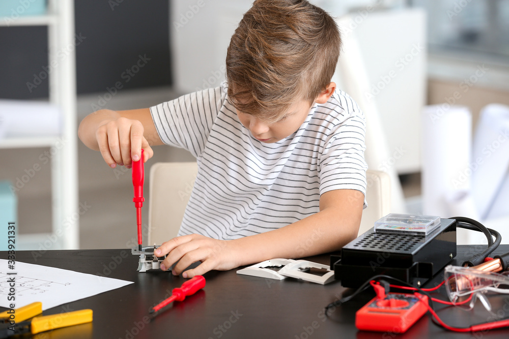 Cute little electrician repairing socket at table