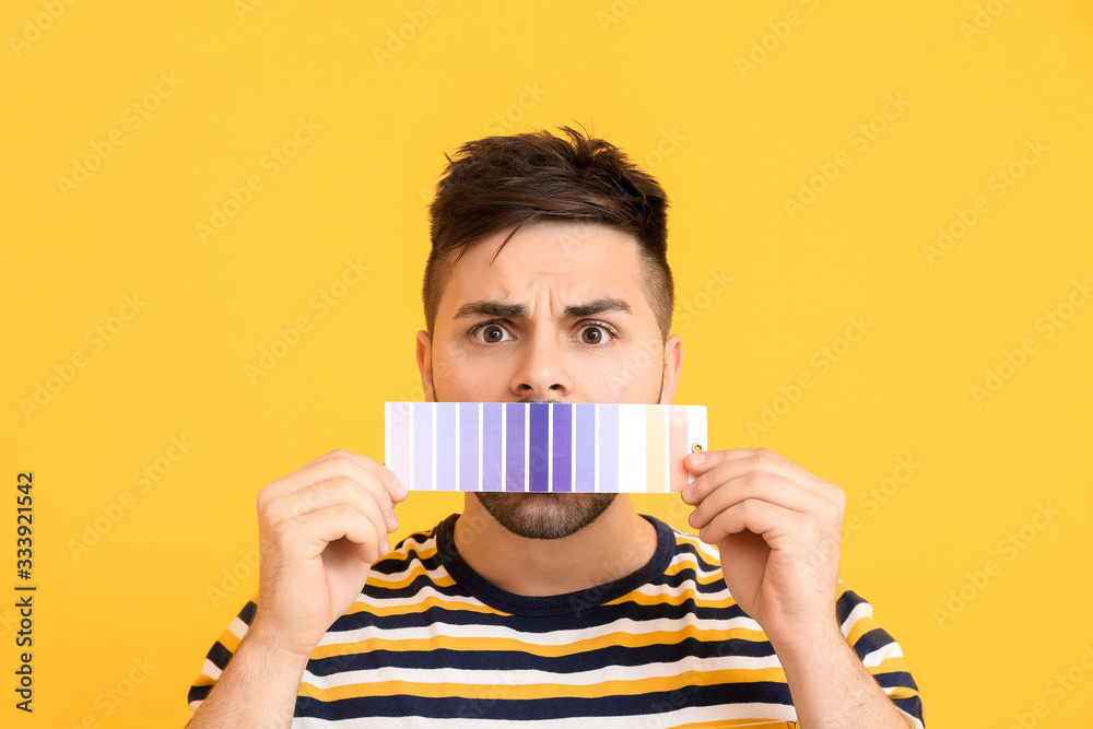 Troubled man with paint palette on color background