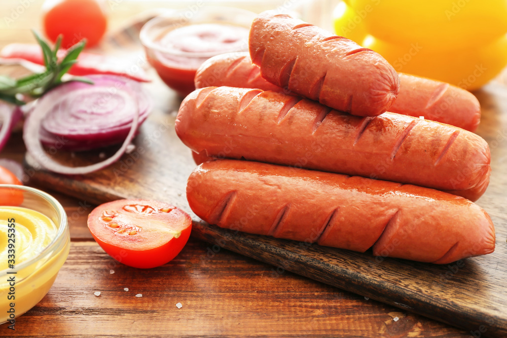 Board with tasty grilled sausages on table