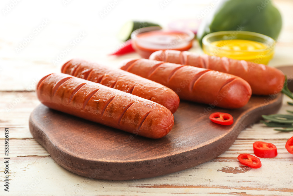 Board with tasty grilled sausages on table