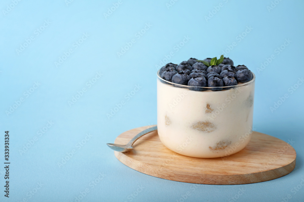 Tasty tiramisu with berries on color background