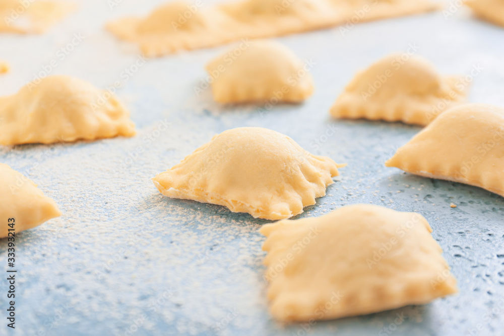 Uncooked ravioli on color background