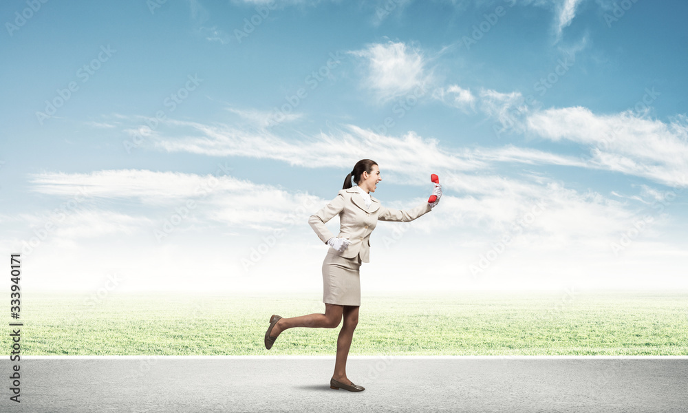 Woman running outdoor with vintage red phone