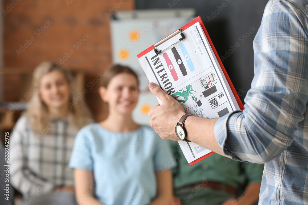 Male interior designer teaching young people in office