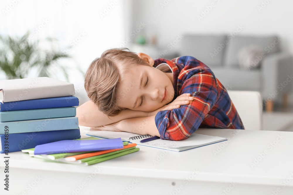 Little boy sleeping at table instead of doing lessons at home