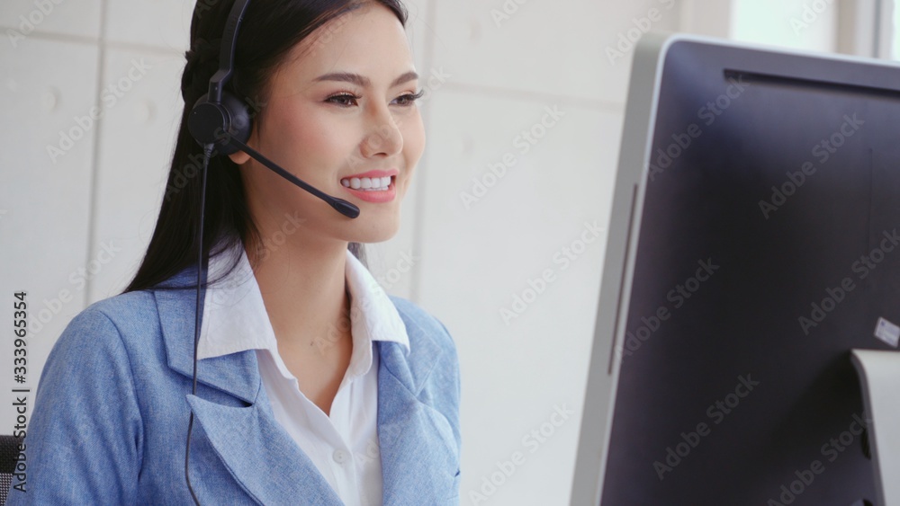 Customer support agent or call center with headset works on desktop computer while supporting the cu