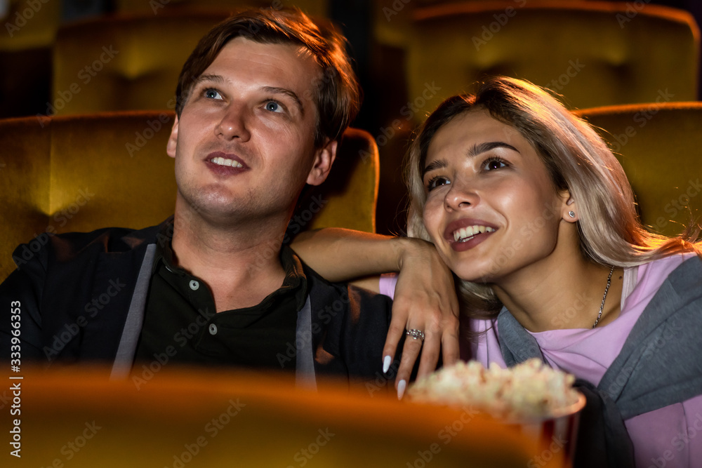 Caucasian lover enjoying to watch movie and eating popcorn together in the cinema