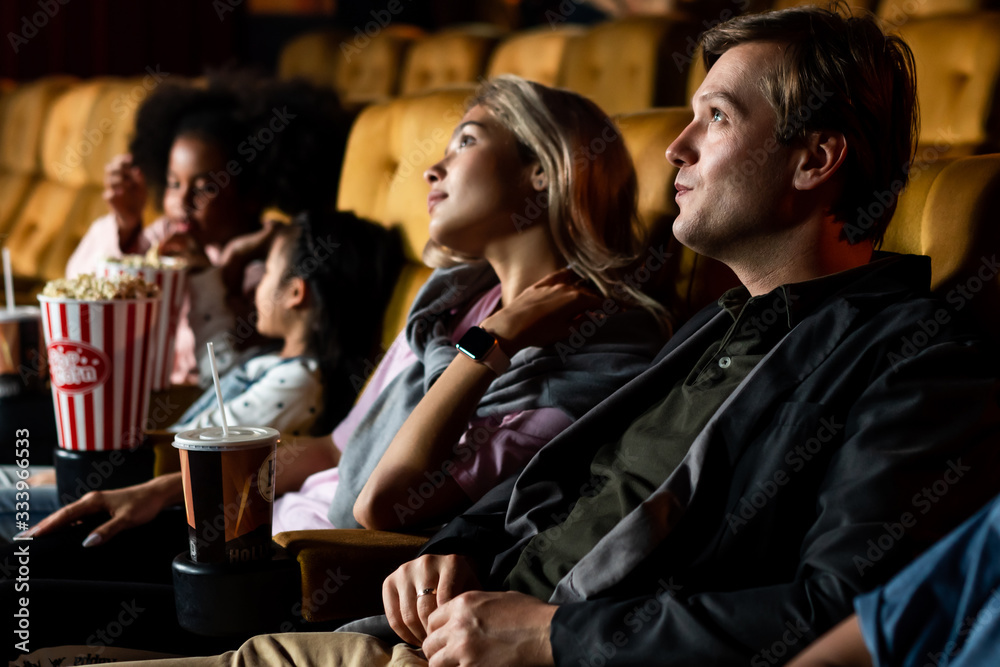 A couple and kids enjoy and casually watching a movie in the cinema