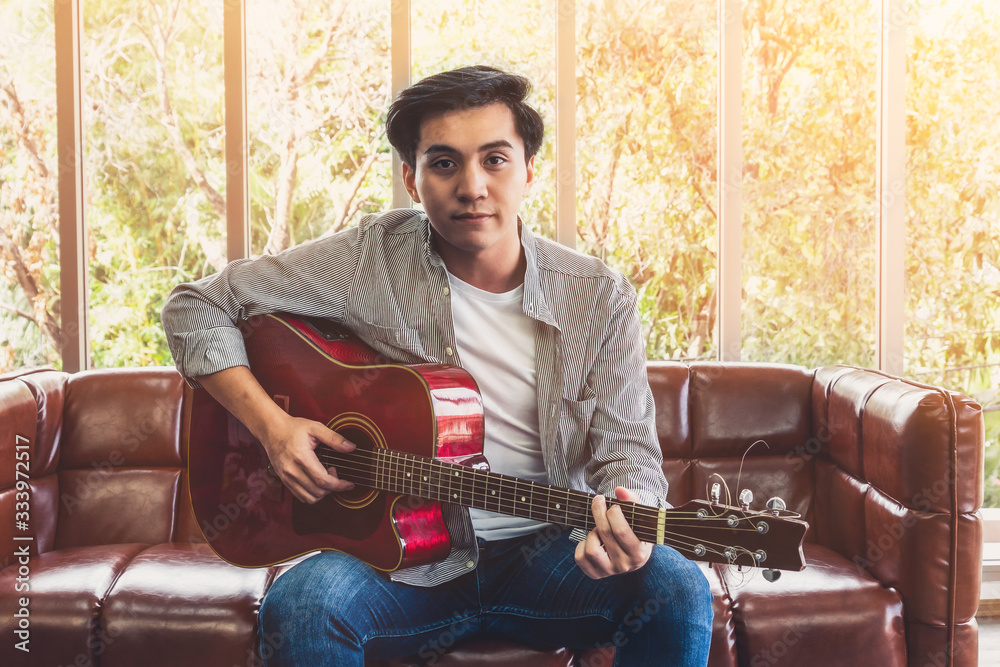 Young guitar player holding his guitar at home. Music and song concept.