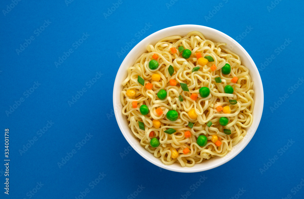 Bowl of instant noodles isolated on blue background, top view