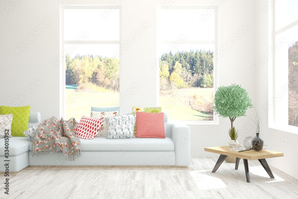 Stylish room in white color with sofa and autumn landscape in window. Scandinavian interior design. 