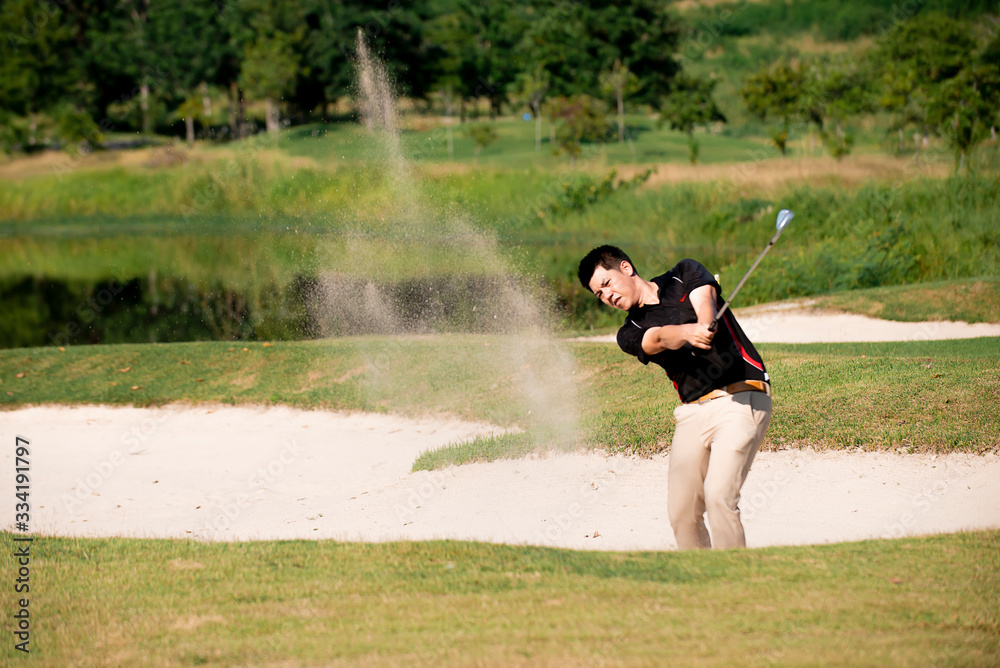 Asian man golfer hitting ball on sand at golf course