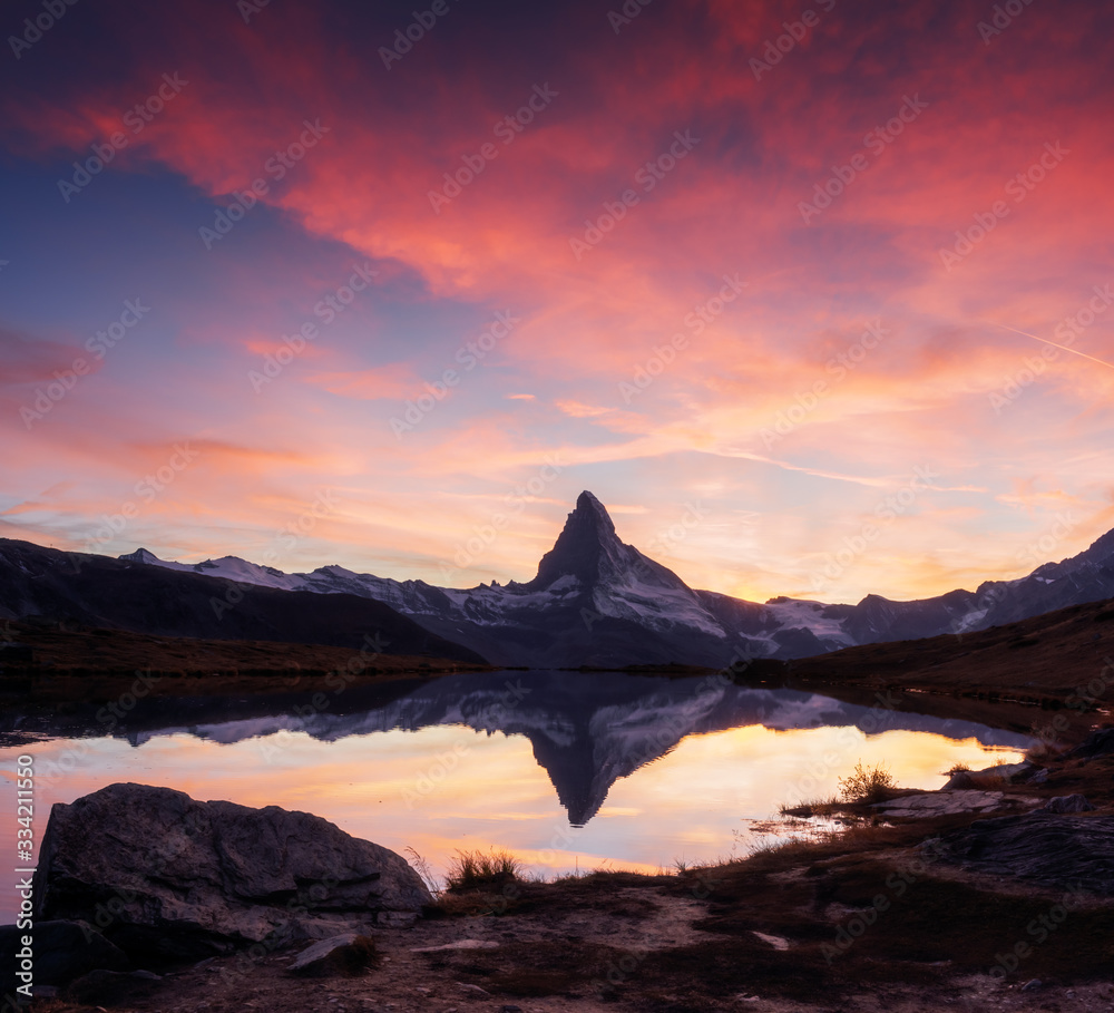 Picturesque landscape with colorful sunrise on Stellisee lake. Snowy Matterhorn Cervino peak with re