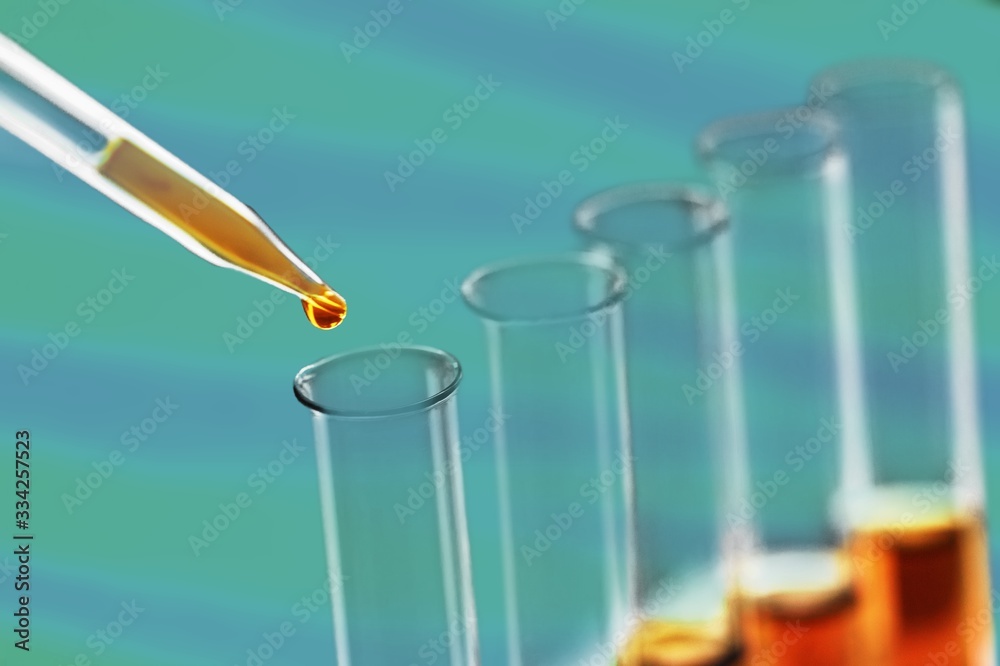 Glass pipette with liquid and scientific test tubes