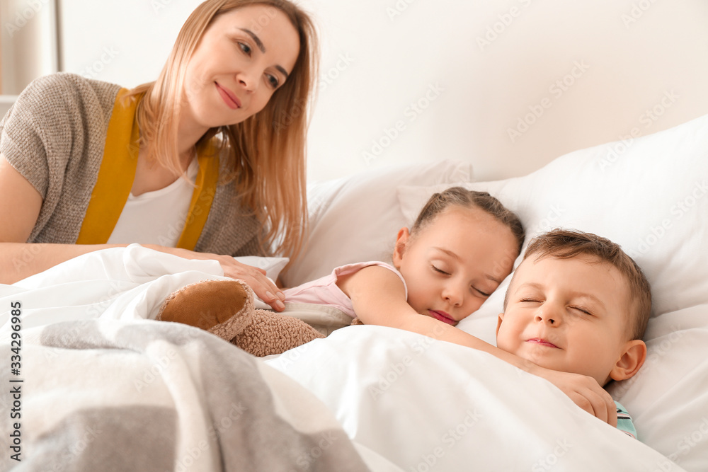 Nanny putting cute little children to bed