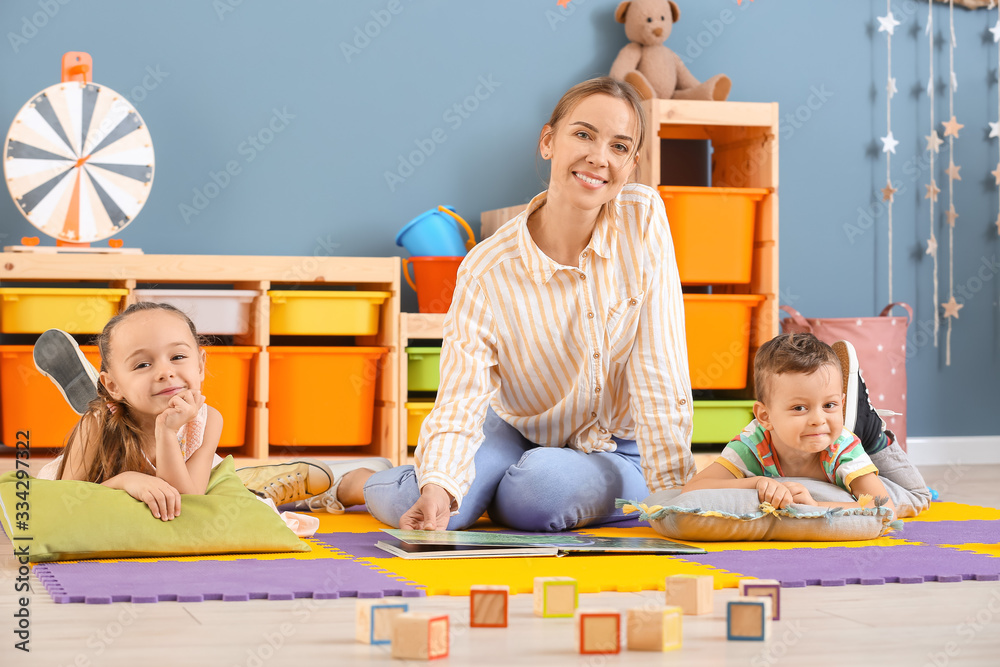 Nanny and cute little children playing at home