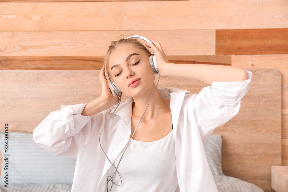 Beautiful young woman listening to music in bedroom