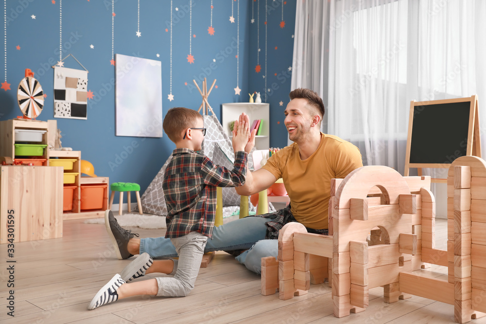 Father and little son playing with take-apart house at home