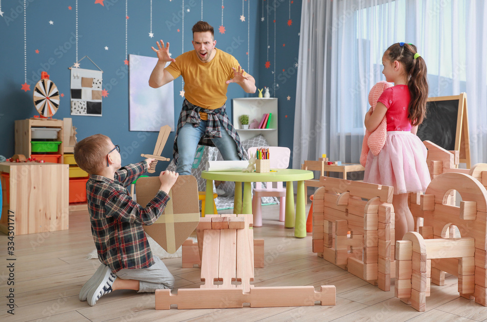 Father and little children playing with take-apart house at home