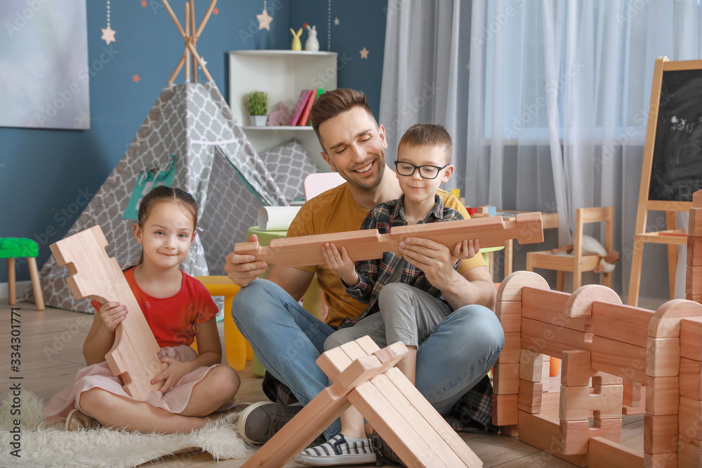 Father and little children playing with take-apart house at home