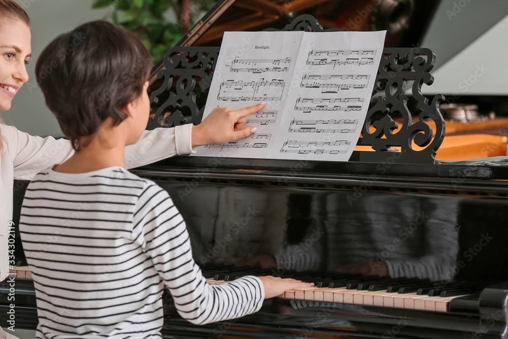 Private music teacher giving piano lessons to little boy