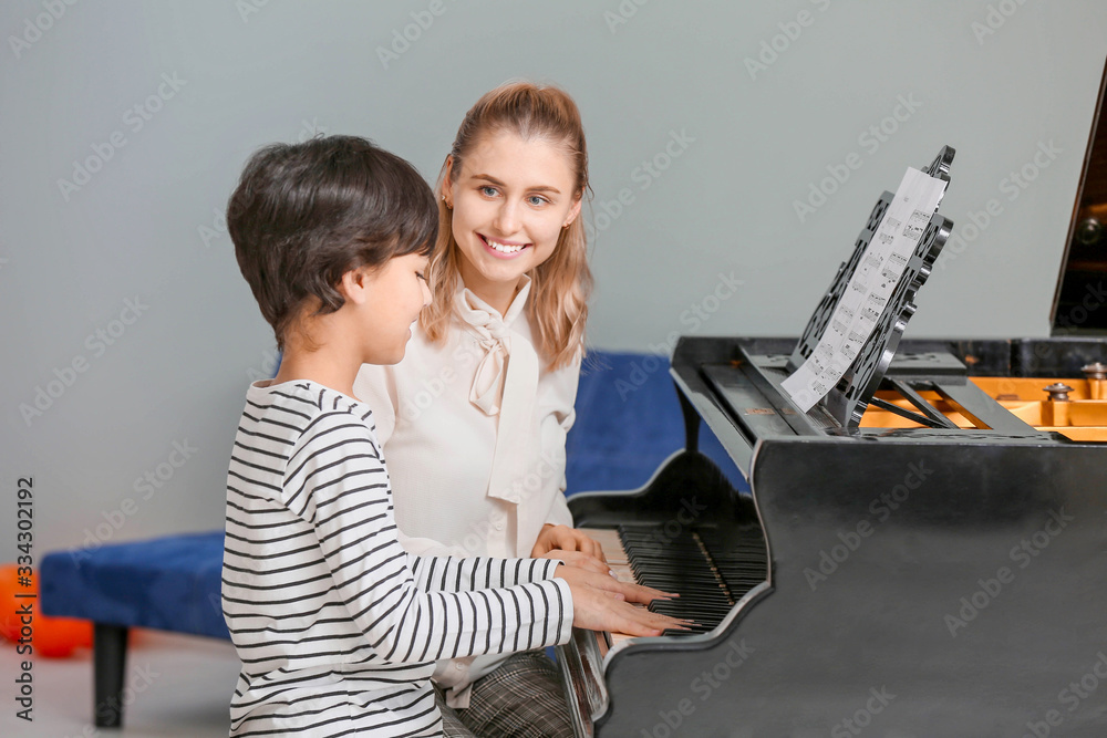 Private music teacher giving piano lessons to little boy