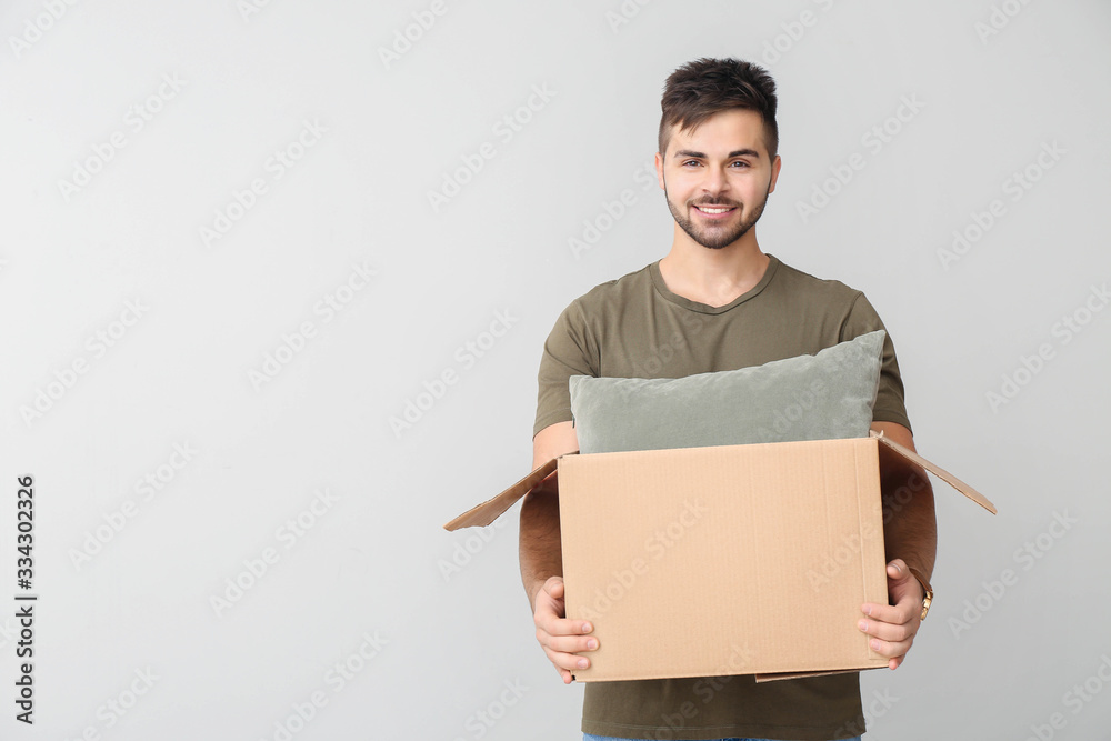 Young man with parcel on light background