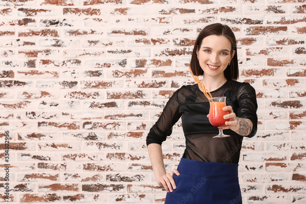 Beautiful female bartender on brick background