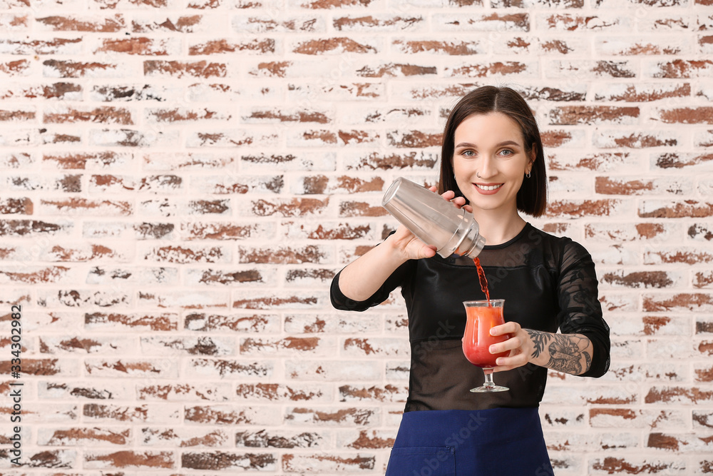 Beautiful female bartender on brick background