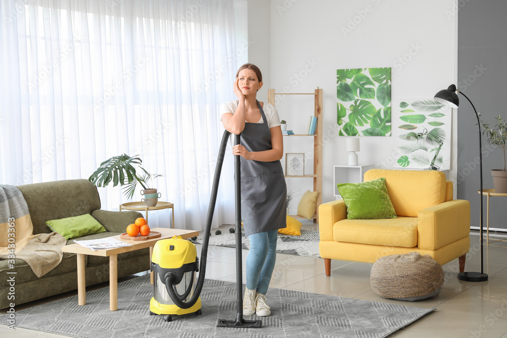 Young woman hoovering floor at home