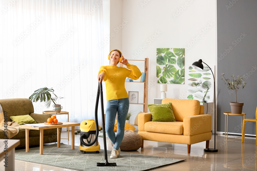 Young woman listening to music while hoovering floor at home