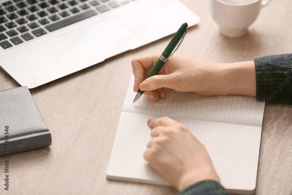 Woman writing something in notebook at table