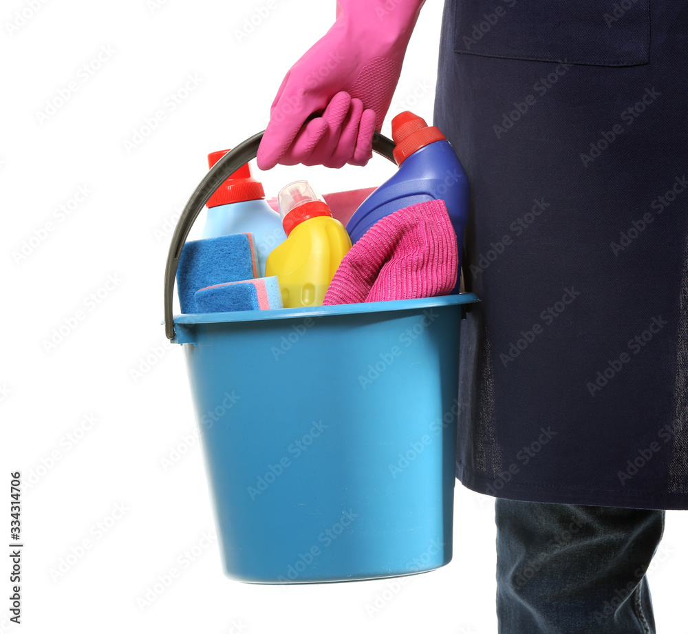 Female janitor with cleaning supplies in bucket on white background