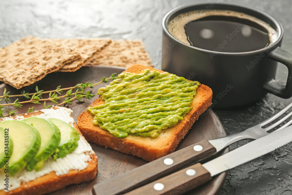 Plate with tasty avocado sandwiches and cup of coffee on table, closeup