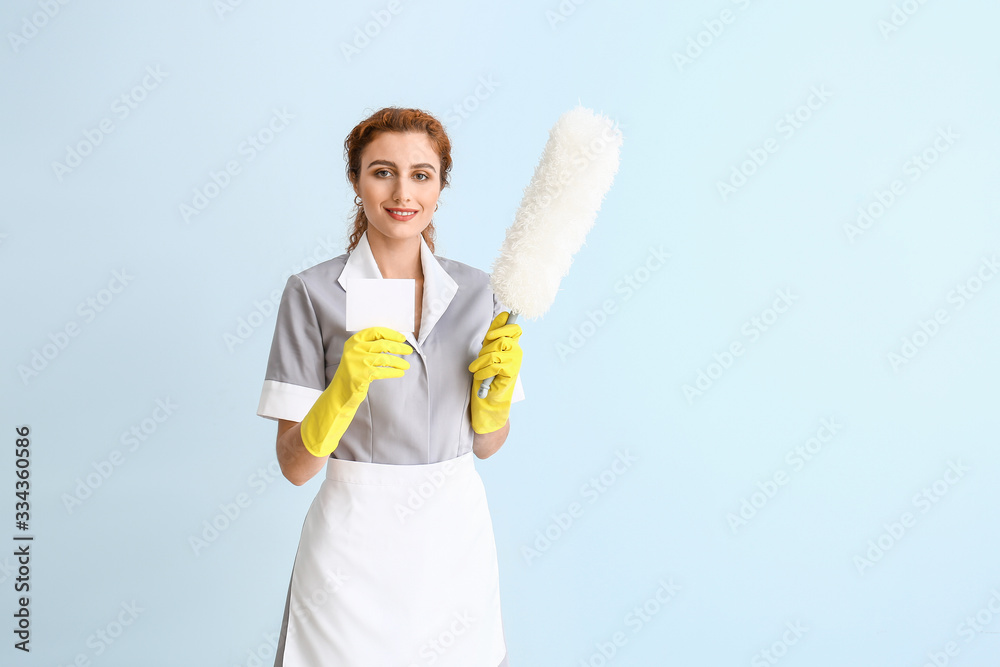 Beautiful young chambermaid with business card on color background