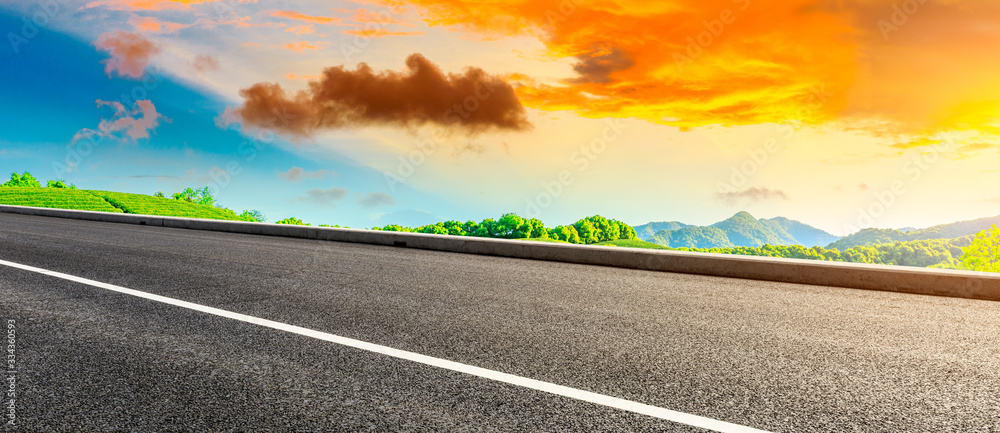 Empty asphalt road and green tea plantation nature landscape at sunset.