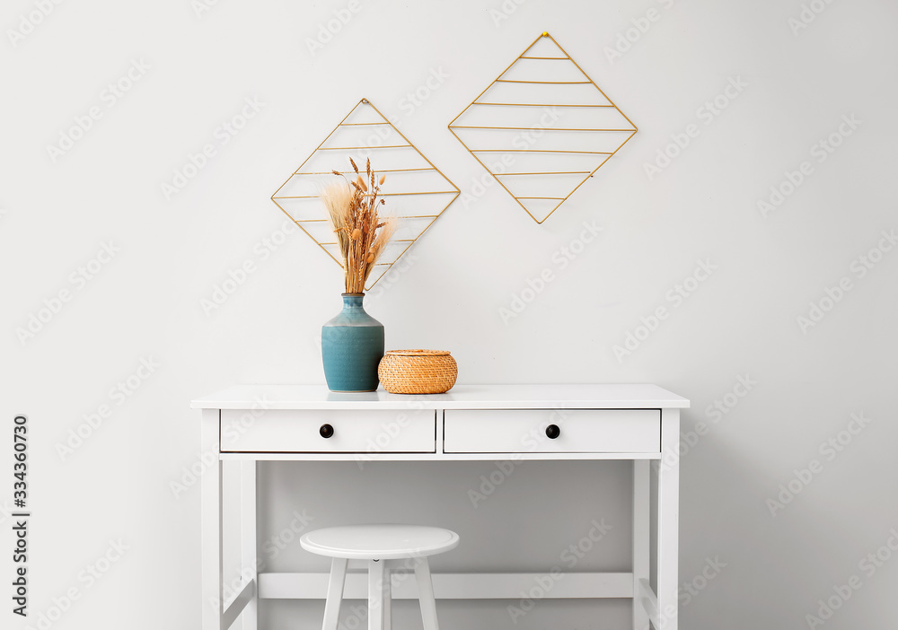 Vase with basket on table near white wall in room